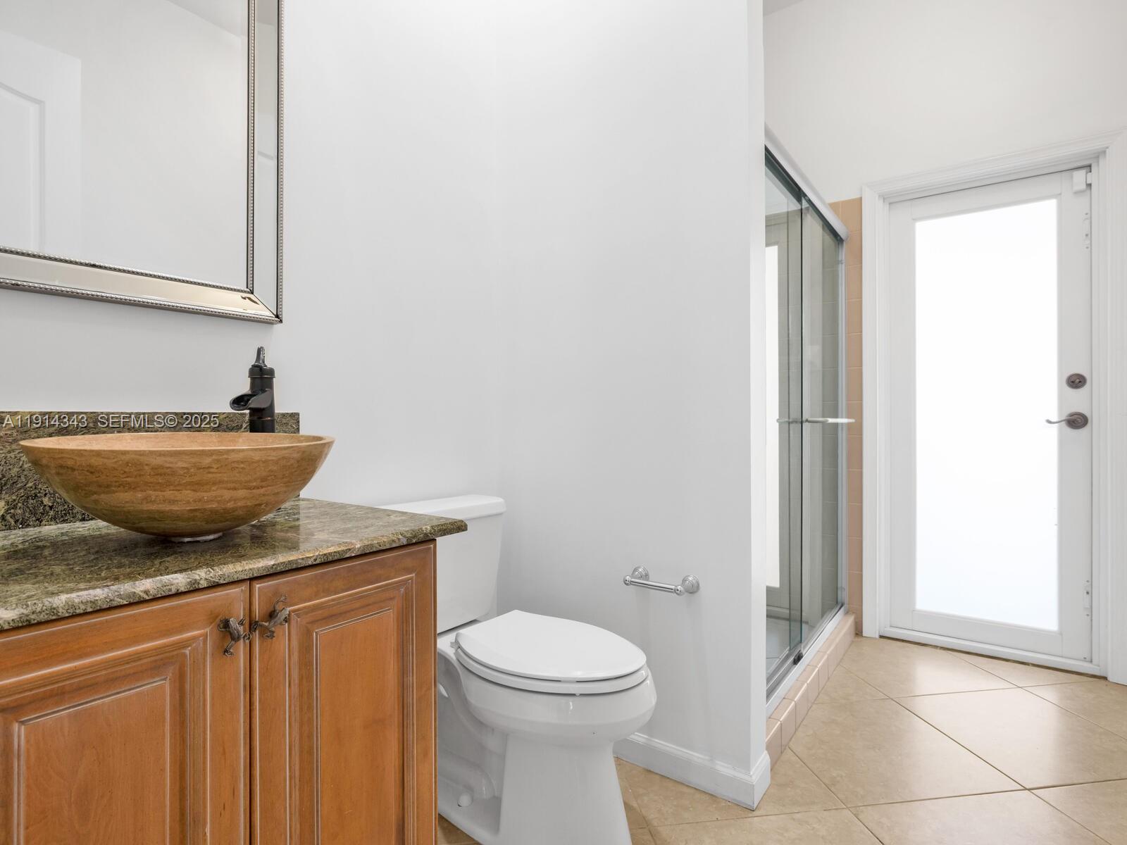 12995 Southwest 40 Street Davie, FL 33330 - Photo 44 of 79 a bathroom with a granite countertop sink toilet and a mirror