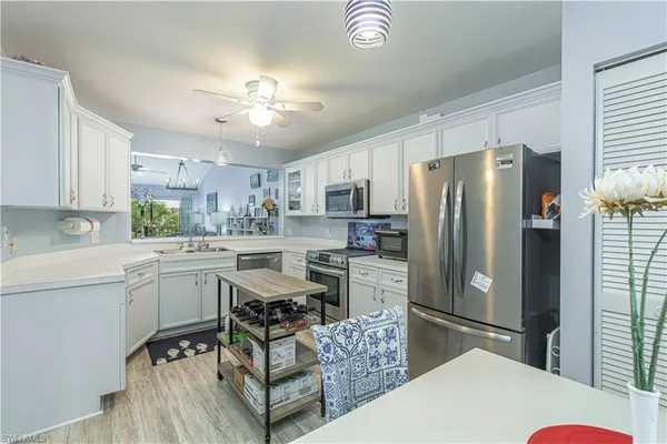 a kitchen with stainless steel appliances a refrigerator a sink dishwasher a stove with white cabinets and wooden floor