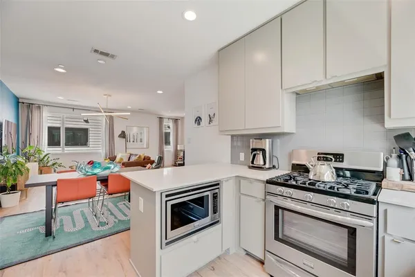 a kitchen with stainless steel appliances a stove a sink cabinets and a wooden floor