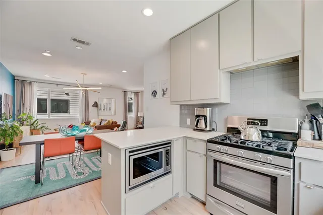 a kitchen with stainless steel appliances a stove a sink cabinets and a wooden floor