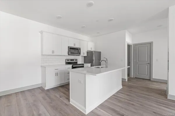 a large white kitchen with a refrigerator a stove top oven a sink and dishwasher