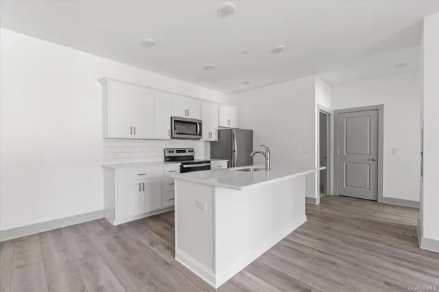 a large white kitchen with a refrigerator a stove top oven a sink and dishwasher