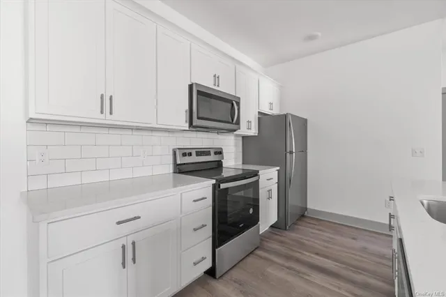a kitchen with stainless steel appliances white cabinets and a stove top oven