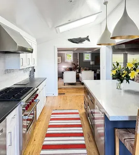 a large kitchen with stainless steel appliances granite countertop a lot of counter top space and wooden floor