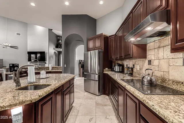 a kitchen with stainless steel appliances granite countertop a sink a stove and a wooden cabinets