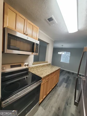 a kitchen with stainless steel appliances kitchen island granite countertop a refrigerator and a stove top oven