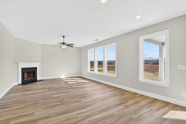 a view of an empty room with wooden floor fireplace and a window
