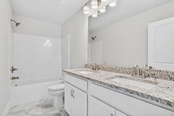 a bathroom with a granite countertop sink a toilet and shower