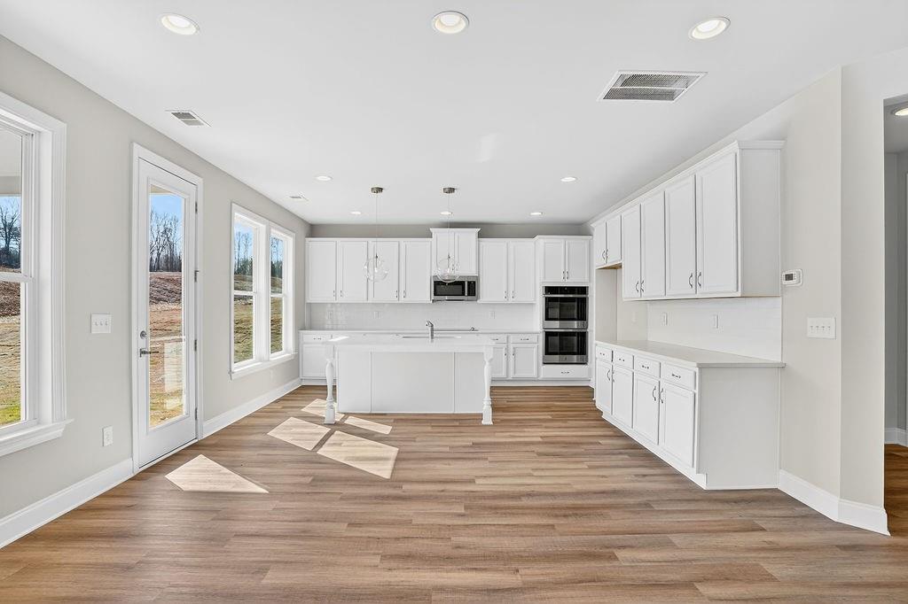140 Classic Overlook Homer, GA 30547 - Photo 10 of 36 a large white kitchen with kitchen island wooden floors and white cabinets