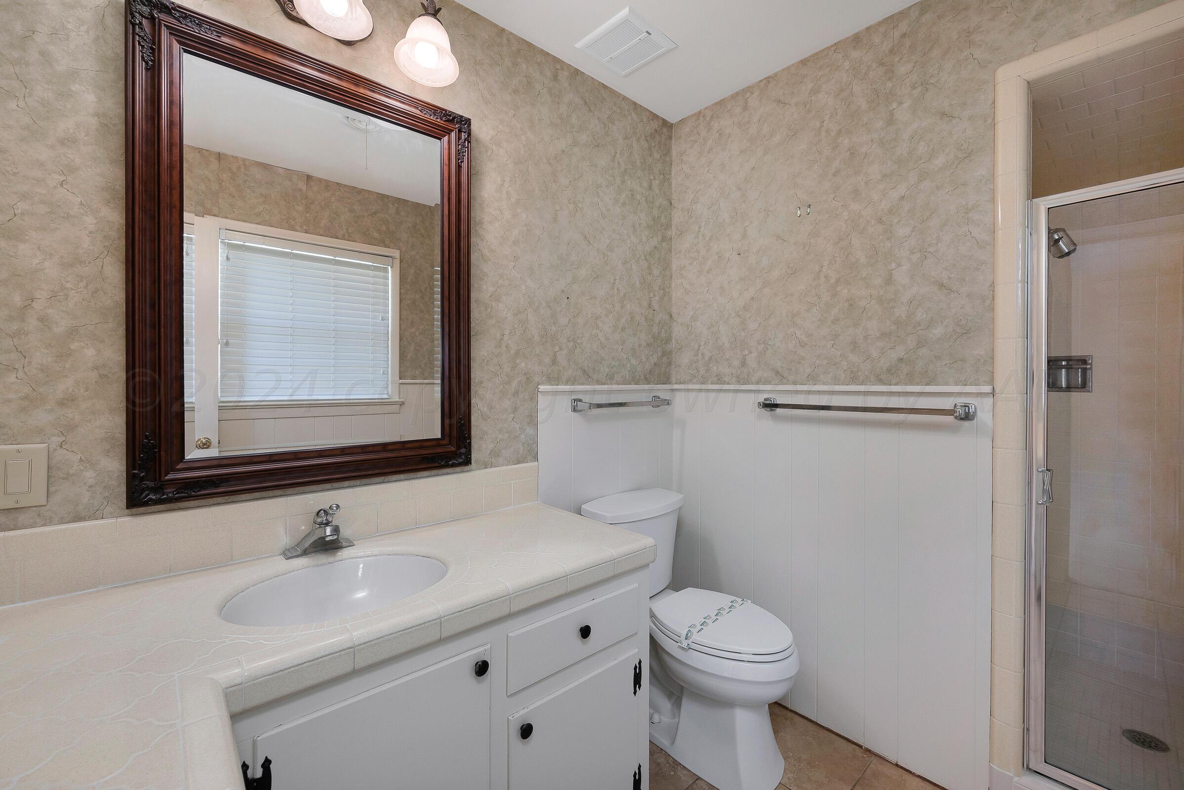 5502 Brinkman Drive Amarillo, TX 79106 - Photo 14 of 22 a bathroom with a toilet a sink and mirror