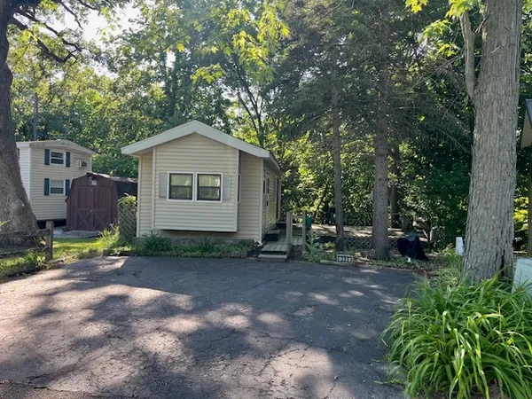 a view of a small house with a tree in the background