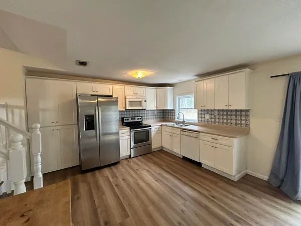 a kitchen with a refrigerator and white cabinets