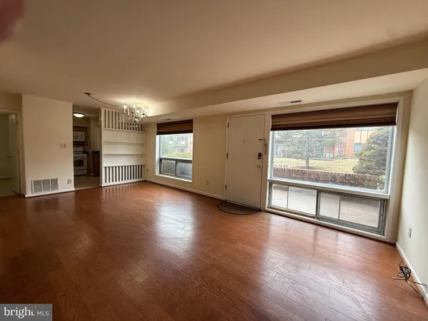 an empty room with wooden floor fireplace and windows