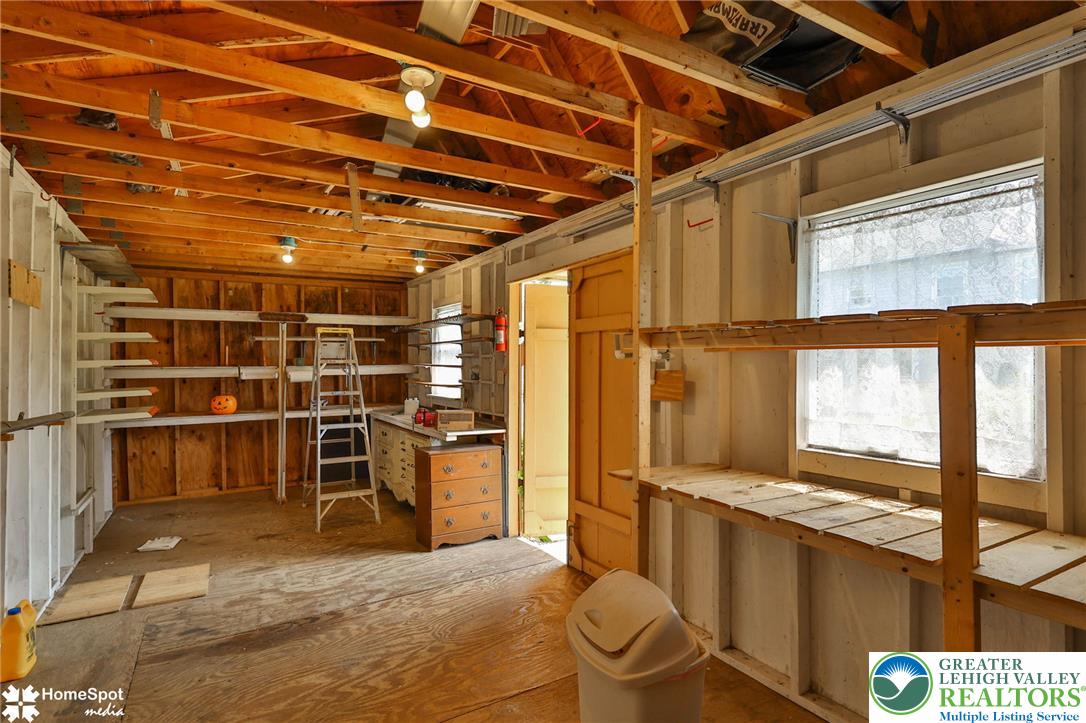 3069 Shakespeare Road Bethlehem, PA 18017 - Photo 48 of 50 A well-lit garage or workshop features exposed wooden beams and ample shelving for storage.