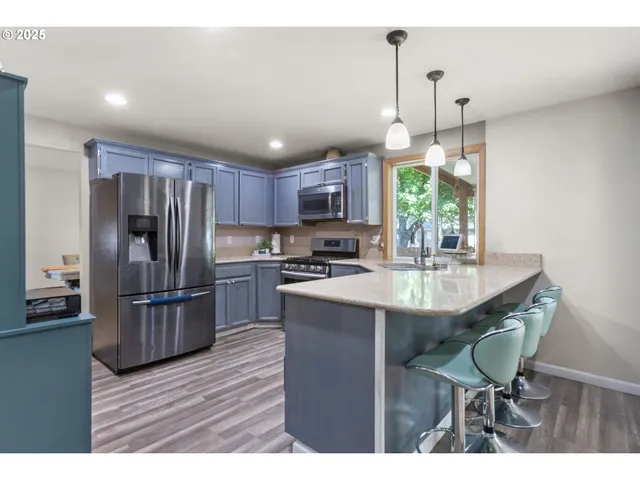 a kitchen with granite countertop a table chairs stainless steel appliances and cabinets