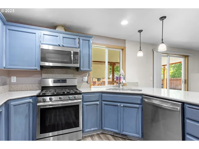 a kitchen with a sink a stove a microwave cabinets and a window