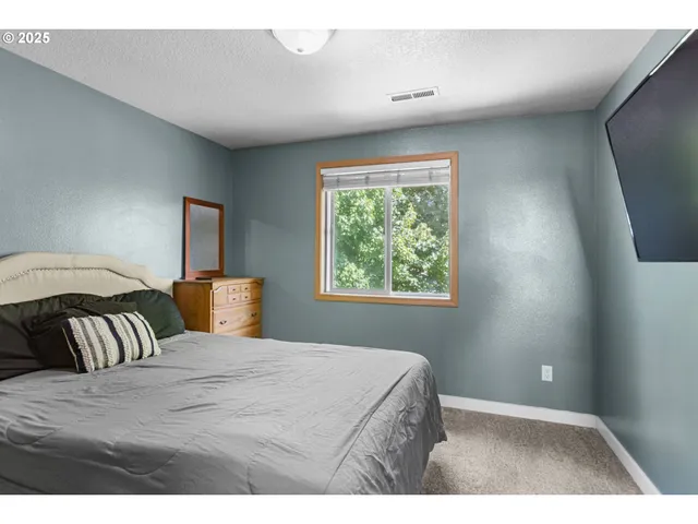 a bedroom with a bed and a large mirror on the dresser