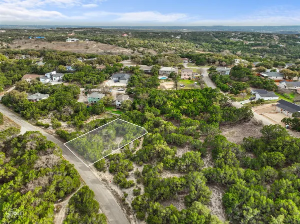 an aerial view of residential houses with outdoor space and trees