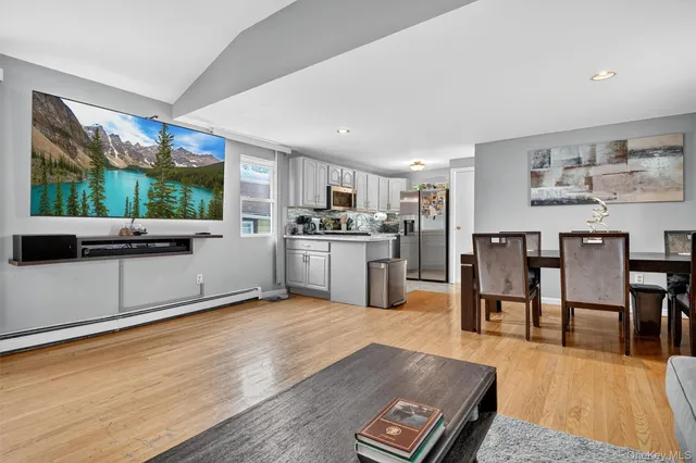 a kitchen with stainless steel appliances granite countertop a stove top oven a sink dishwasher a dining table and chairs with wooden floor