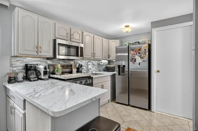 a kitchen with granite countertop a refrigerator stove and microwave