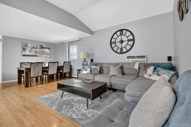 a living room with furniture a clock on wall and a table