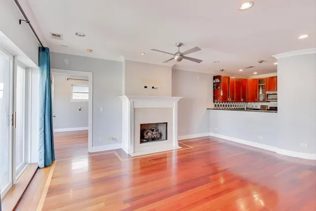 a view of an empty room with wooden floor fireplace and a window