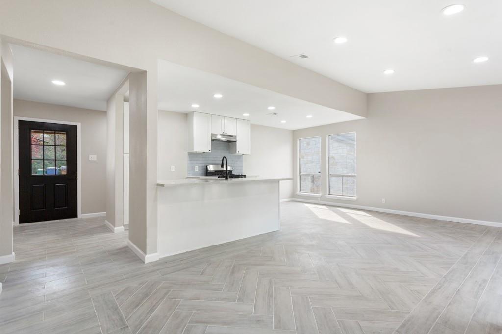 9604 Crown Ridge Road Austin, TX 78753 - Photo 5 of 24 Herringbone pattern tile flooring extends across a generous open-concept living area with a functional kitchen island.