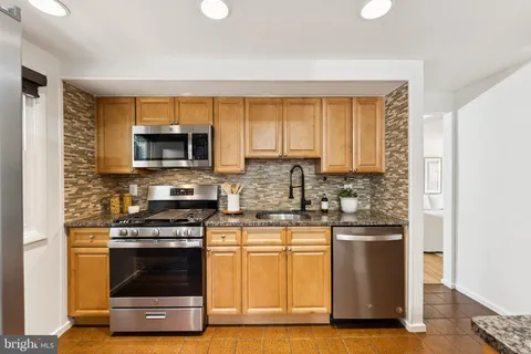 a kitchen with kitchen island granite countertop a stove and a microwave