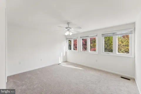 an empty room with a ceiling fan and a window