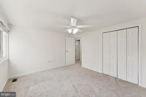 an empty room with windows and fan