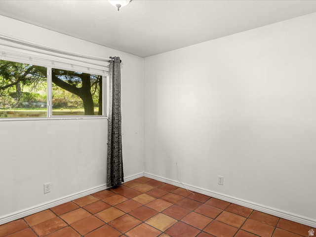 15680 North Beaver Dam Road Collinston, UT 84306 - Photo 27 of 49 Terracotta tile flooring complemented by a window with exterior tree views, white walls, and a ceiling-mounted light fixture