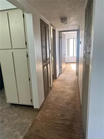 a view of a hallway with wooden floor and cabinets