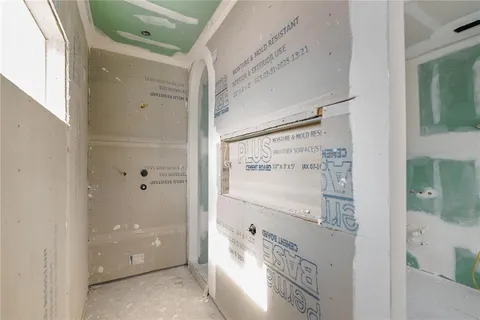 a view of a hallway with wooden floor and a bathroom