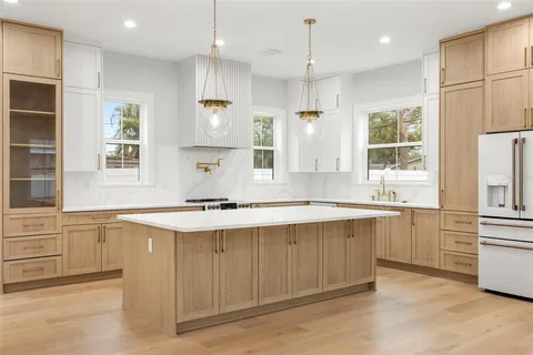 a large kitchen with stainless steel appliances granite countertop a sink a stove and a refrigerator