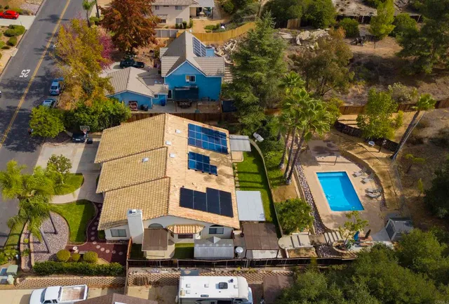an aerial view of a house with swimming pool and large trees