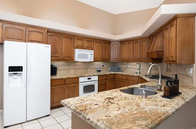 a kitchen with granite countertop a refrigerator stove top oven a sink and dishwasher