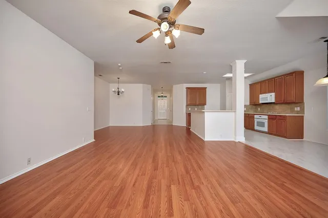 a view of empty room with wooden floor and kitchen view