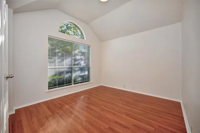 a view of an empty room with a window and a wooden floor