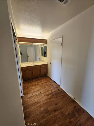 a view of an empty room with wooden floor and cabinet