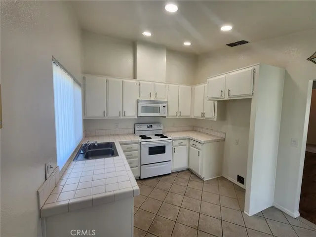 a kitchen with granite countertop a sink stove and cabinets