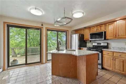 a kitchen with stainless steel appliances granite countertop a stove top oven a sink dishwasher a dining table and chairs with wooden floor