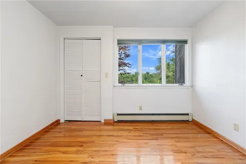 an empty room with wooden floor and fan