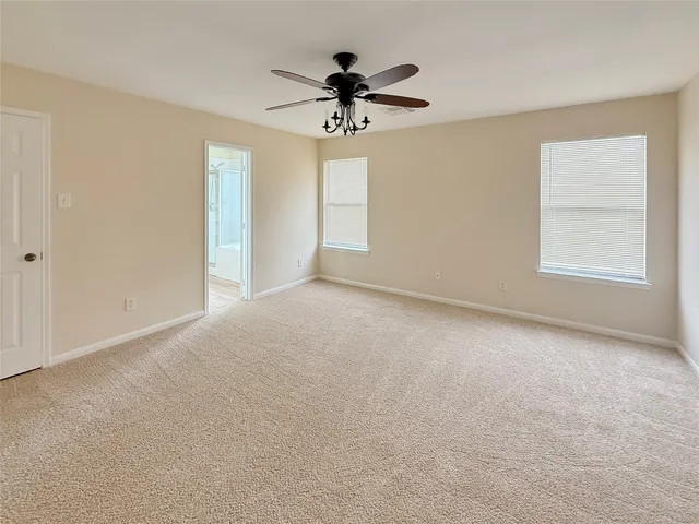 an empty room with chandelier fan and windows