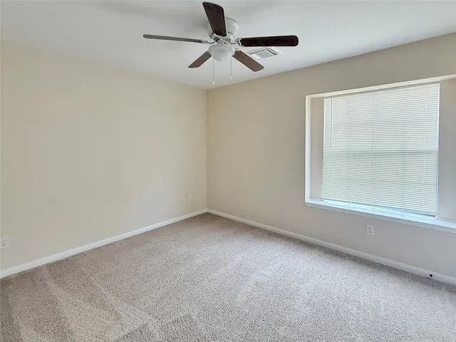 an empty room with a window and a fan