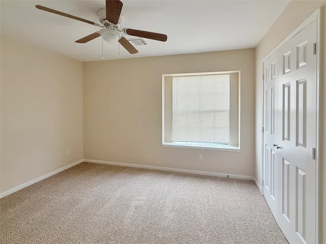 an empty room with a window and a fan