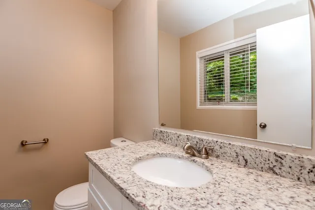a bathroom with a granite countertop sink toilet and mirror