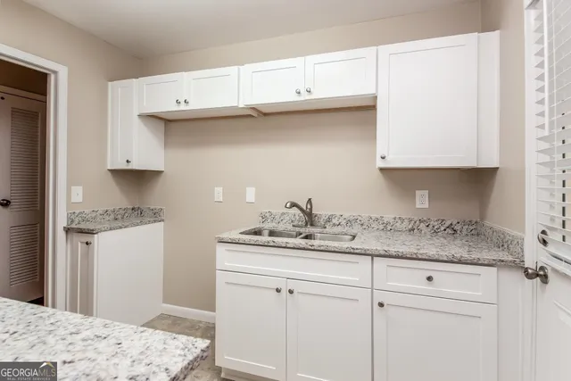 a kitchen with granite countertop a sink cabinets and stainless steel appliances