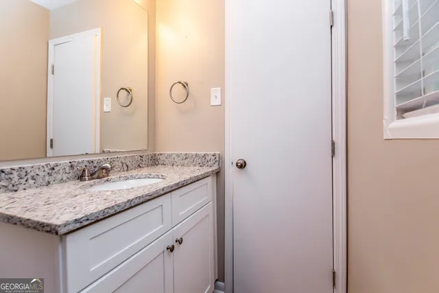 a bathroom with a granite countertop sink and a mirror