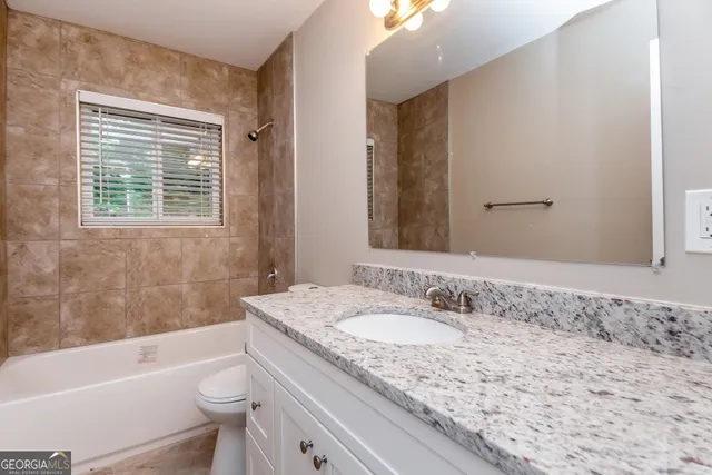 a bathroom with a granite countertop sink a toilet and bathtub