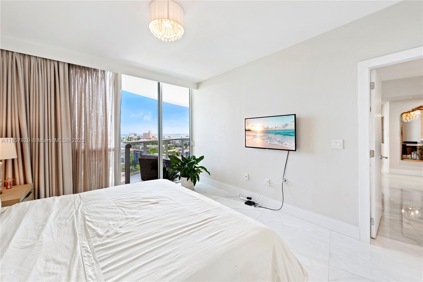 400 Alton Road, Unit 1405 Miami Beach, FL 33139 - Photo 9 of 18 a bedroom with a large bed and a chandelier